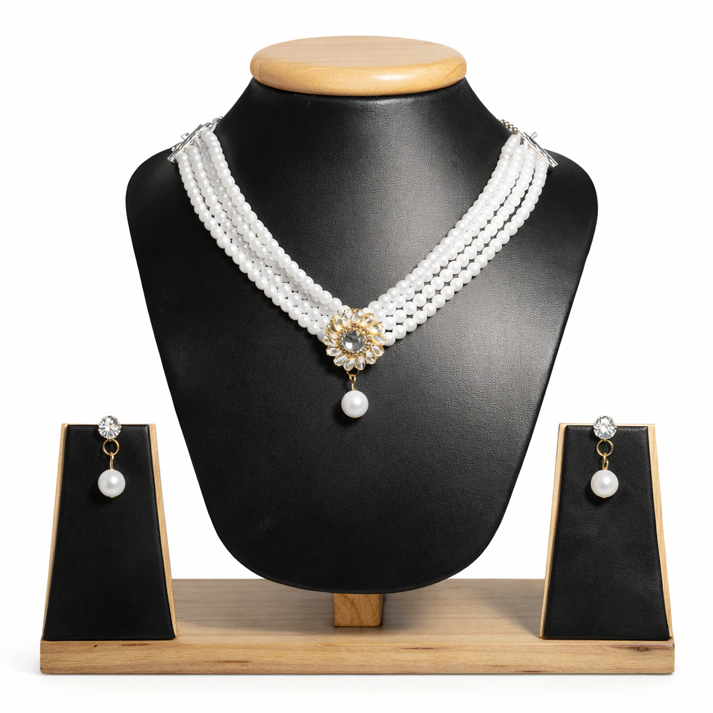 Luxurious design: Four strands of lustrous white pearls converge at a gold-toned floral centerpiece adorned with sparkling crystals and a dangling pearl drop.