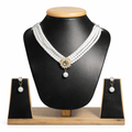 Luxurious design: Four strands of lustrous white pearls converge at a gold-toned floral centerpiece adorned with sparkling crystals and a dangling pearl drop.